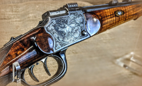 A sample consignment firearm, with intricate engravings featuring two deer and colorful wood grain, previously available at Liberty Tree Guns in Carthage, MO.
